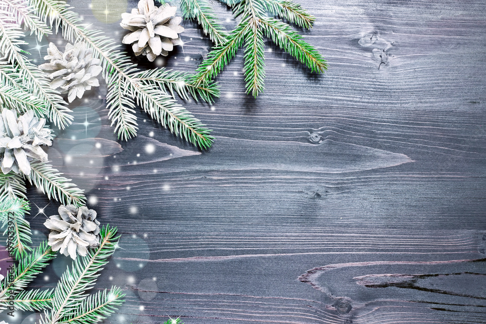 Christmas fir tree with cones and snow on a wooden background, selective focus and place for text. Toned Christmas fir tree with cones and snow on a wooden background, selective focus and place for text. Toned