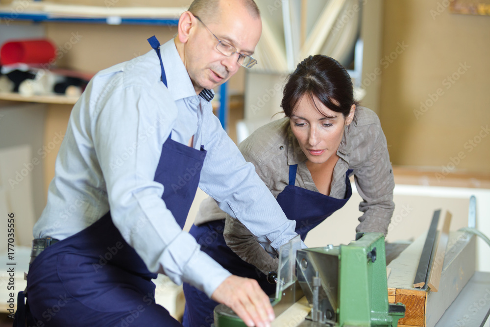 Obraz premium man and woman using wood cutting machien