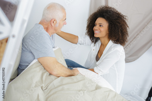 female doctor with senior male patient lying in bed