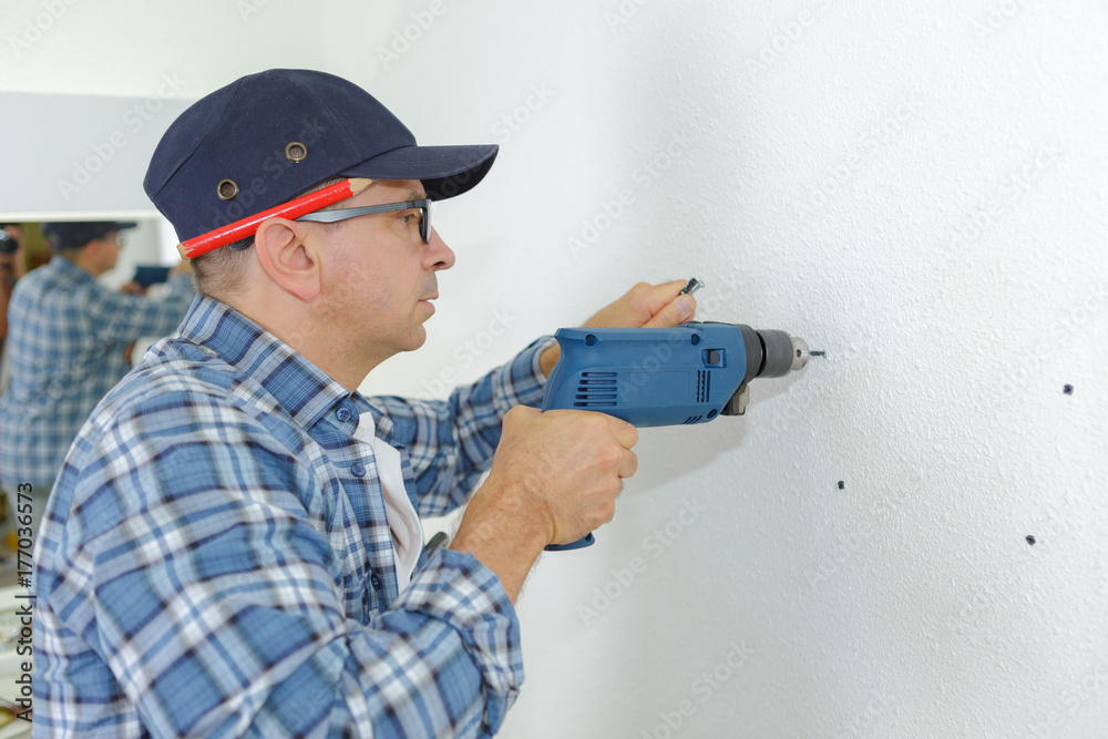 man drilling the wall with impact drill man drilling the wall with impact drill