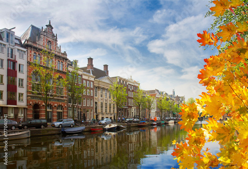 One of canals in Amsterdam old town with green trees at autumn day, Holland