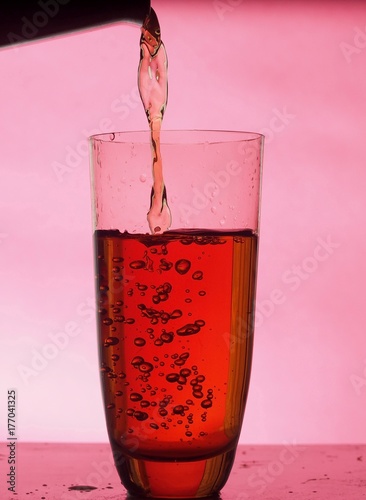 In a clear glass filled with drink. The on Burgundy background.