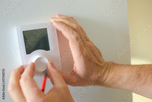 person adjusting thermostat control on a electric heater
