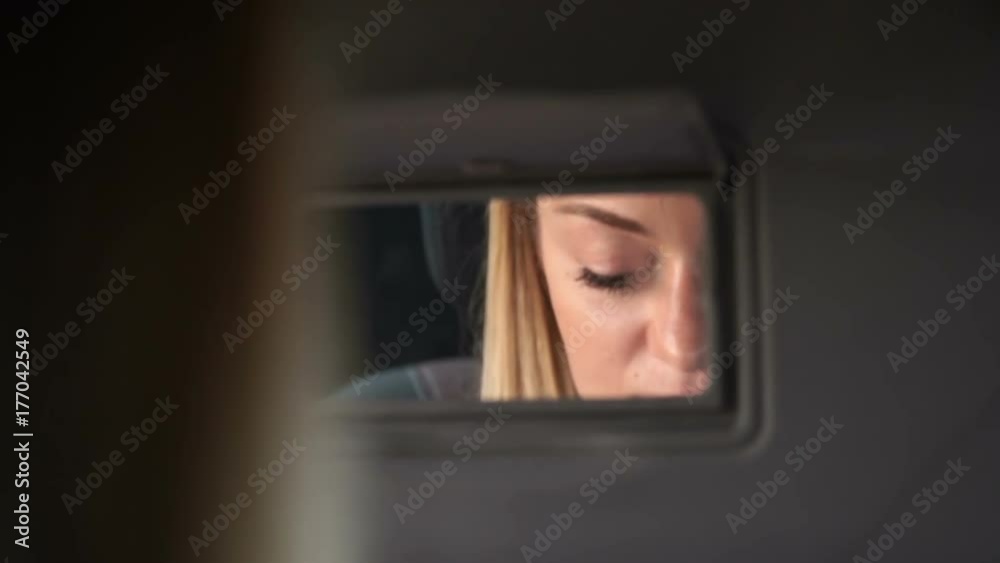 Young blond woman paints her lips in the car. The sun illuminates the face. Close up. Young blond woman paints her lips in the car. The sun illuminates the face. Close up.