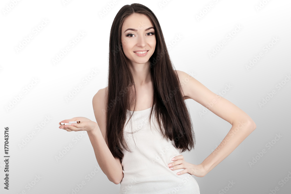No smoking Portrait of a young woman with cigarettes in her arms. Humiliating sagayad. Caution against smoking. Lowers finger to bottom. On a gray background. No smoking Portrait of a young woman with cigarettes in her arms. Humiliating sagayad. Caution against smoking. Lowers finger to bottom. On a gray background.