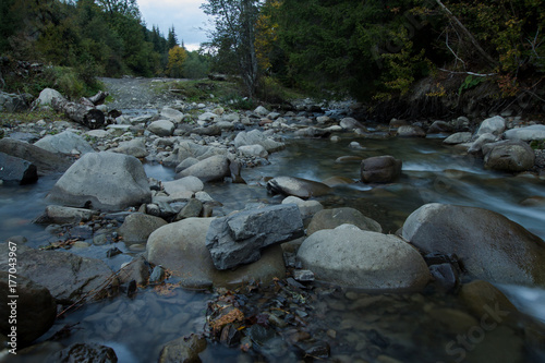mountain river with stones, forest and rocks background 