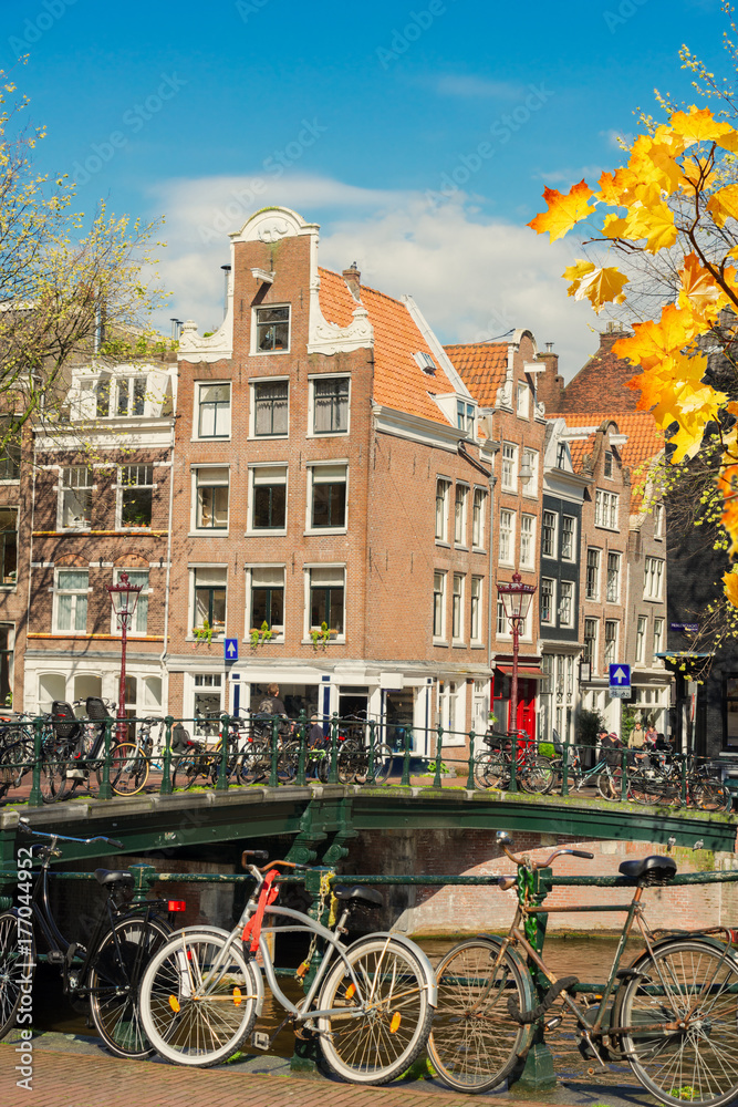 Houses and bicycles standing next to canal in Amsterdam, Netherlands at autumn day