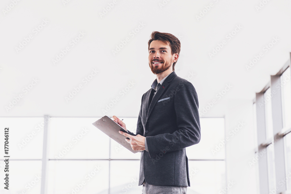 Young businessman on the background of modern architecture writes notes in notebook Young businessman on the background of modern architecture writes notes in notebook