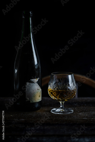 Vintage sherry bottle and crystal glass in natural low light setting.