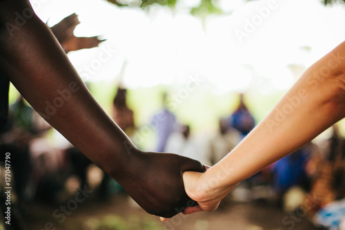 African Woman and American Woman Hold Hands in Uganda photo