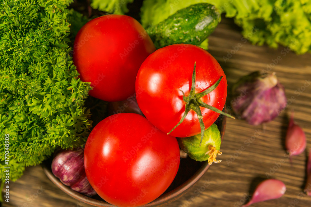Fresh ripe tomatoes on a wooden table with a green salad on the background. Fresh vegetables. Delicious vegetarian food. Salad. Fresh ripe tomatoes on a wooden table with a green salad on the background. Fresh vegetables. Delicious vegetarian food. Salad.