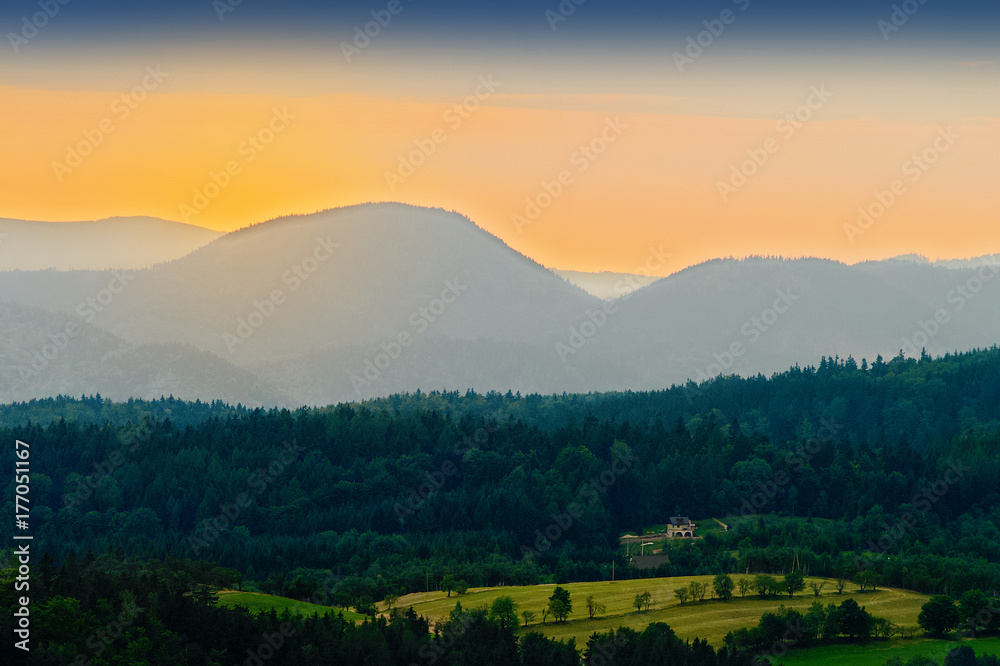 Vast panorama view of valley in the Owl Mountains with silhouette of Sudetes mountain range at dusk. Mountainous countryside landscape in south-west Poland.