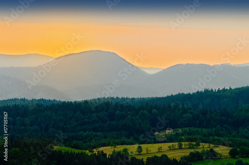 Vast panorama view of valley in the Owl Mountains with silhouette of Sudetes mountain range at dusk. Mountainous countryside landscape in south-west Poland.