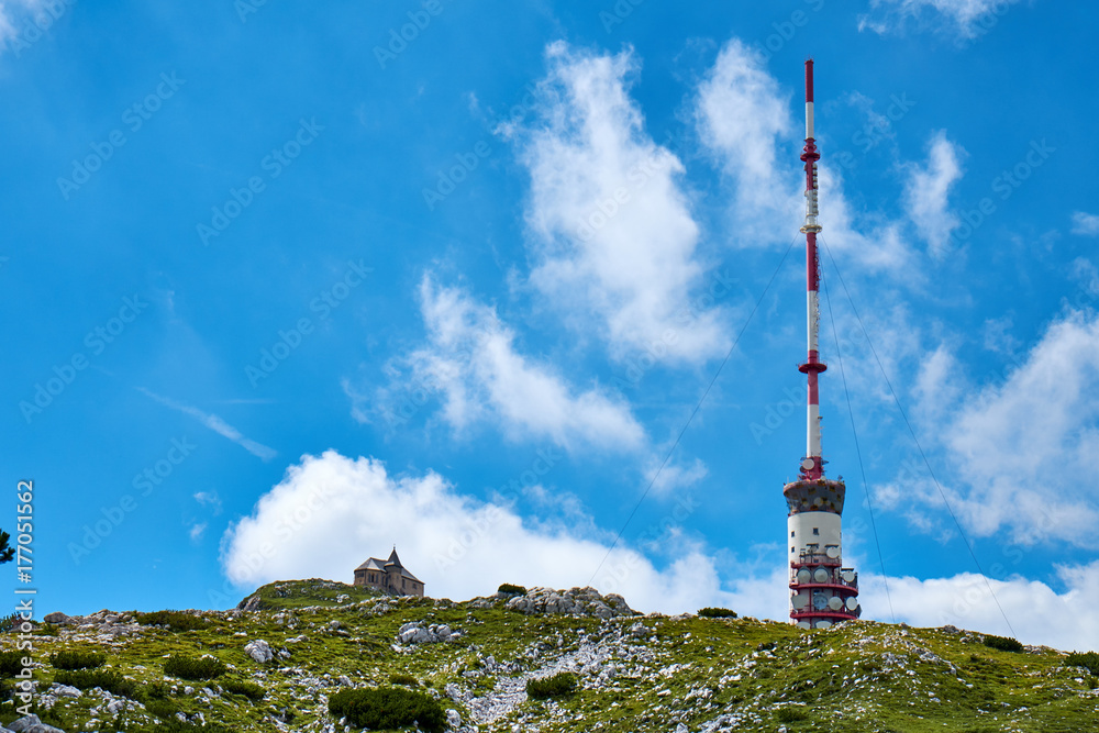 Low angle shot of radio tower and german chapel Maria am Stein on the top of Dobratsch peak in the austrian alps near Villach
