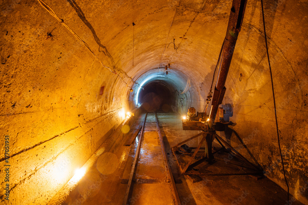 Abandoned round underground technical mine tunnel with a crane and narrow-gauge railway