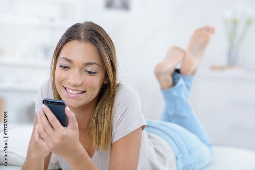 beautiful young woman lying on the bed and texting beautiful young woman lying on the bed and texting