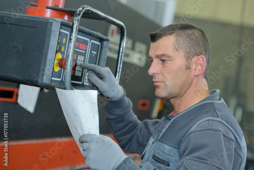 worker entering numbers from instructions into machinery