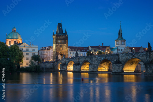 Lit Charles Bridge  Karluv most  and old buildings at the Old Town and their reflections on the Vltava River in Prague  Czech Republic  at dusk.