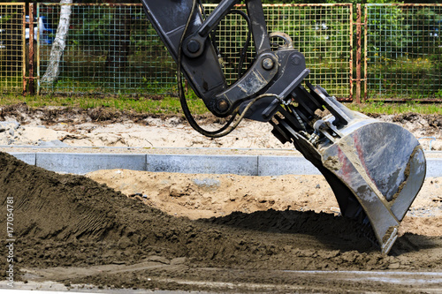 Construction works. Excavator evens out the ground.