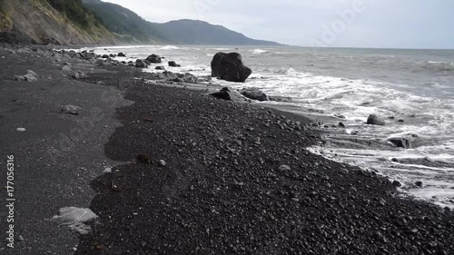 Rocky beach with mountains and crashing waves in California. Stabilized walk forward. photo