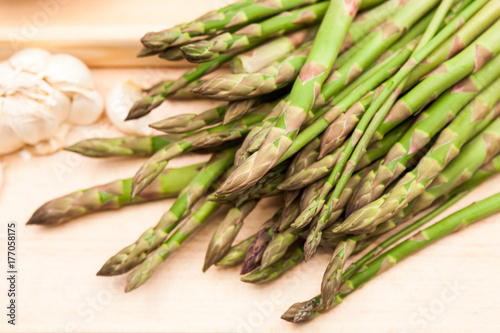 Fresh asparagus stems and garlic on a wooden board
