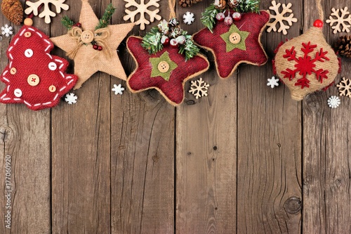 Rustic Christmas top border with burlap and cloth ornaments over an aged wood background