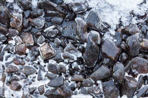 Small rocks covered in ice at lake shore