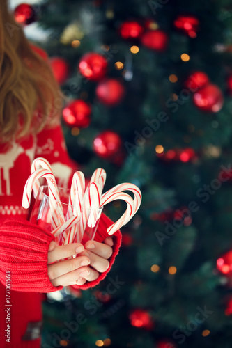 Girl holding stack of peppermint candy canes. Christmas holiday concept. Holiday background