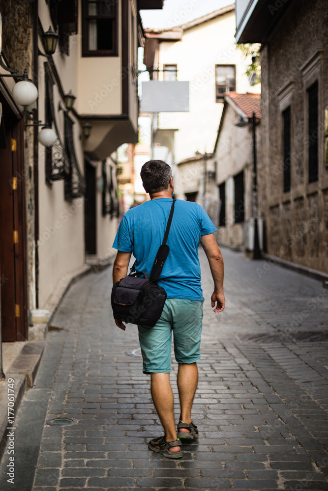 Traveller with camera bag walking through the narrow streets of Traveller with camera bag walking through the narrow streets of