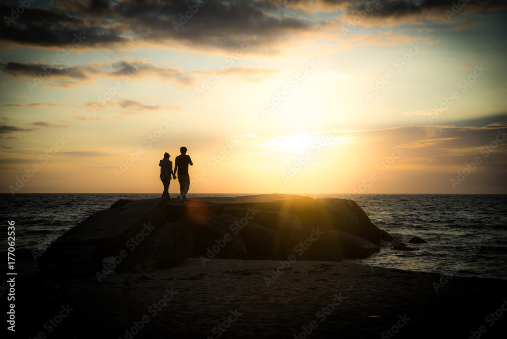 夕焼けの海を散歩するカップル