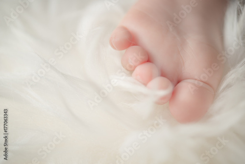 Small bare feet of a little baby girl or boy. Sleeping newborn child. Bare feet of a cute newborn baby in warm white blanket.