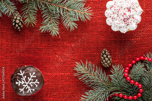 christmas decorated cupcakes at red burlap background top view