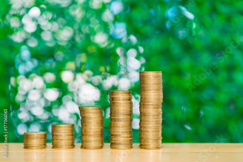 Step of coins stacks on table in garden with green background, finance and business concept.