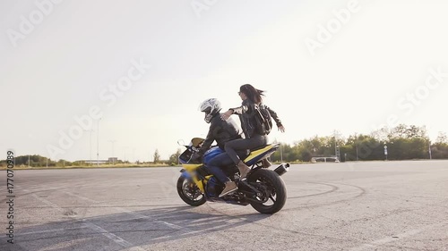 Young beautiful biker family at sunset riding on their motorcycle. Leather clothes, backpack, jeans photo