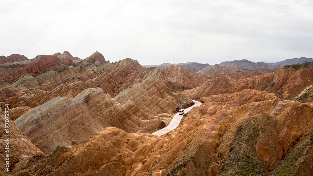 The bus is riding in the middle of rainbow mountains of china (Zhangye Danxia landform Geological park), Zhangye, Gansu province, which was named a UNESCO world heritage site in 2009.