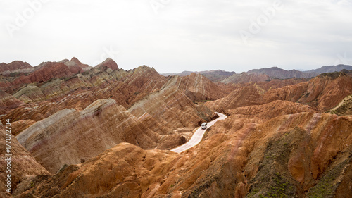 The bus is riding in the middle of rainbow mountains of china (Zhangye Danxia landform Geological park), Zhangye, Gansu province, which was named a UNESCO world heritage site in 2009.