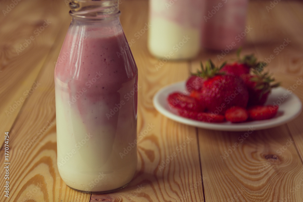 Smoothie with strawberry in bottles on wooden table Smoothie with strawberry in bottles on wooden table