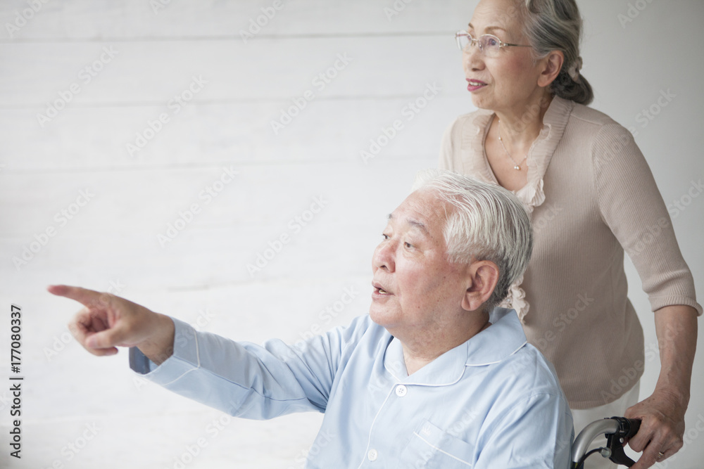 A husband who points to a window with a woman who pushes a wheelchair A husband who points to a window with a woman who pushes a wheelchair