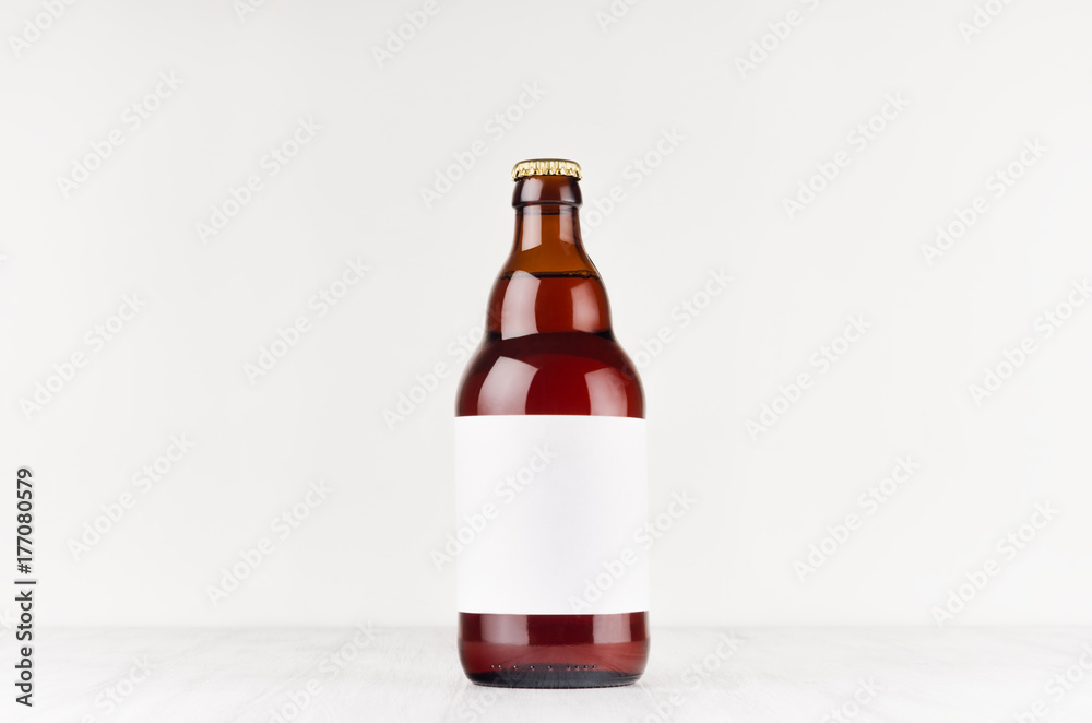 Brown belgian steinie beer bottle 500ml with blank white label on white wooden board, mock up. Template for advertising, design, branding identity. Brown belgian steinie beer bottle 500ml with blank white label on white wooden board, mock up. Template for advertising, design, branding identity.