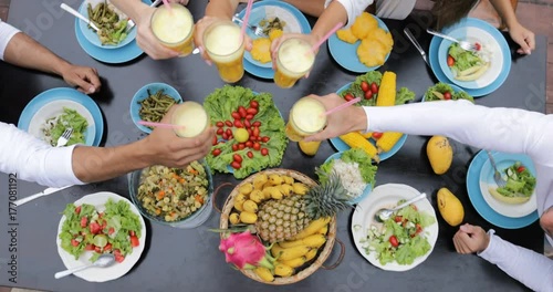 People Clink Juice Glasses, Table With Dishes Of Tropical Fruits And Salad Top Angle View Friends Eating Healthy Vegetarian Food Slow Motion 60