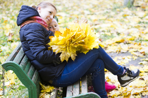 Beautiful young mother and daughter portrait in autumn park with a bouquet of autumn maple leaves