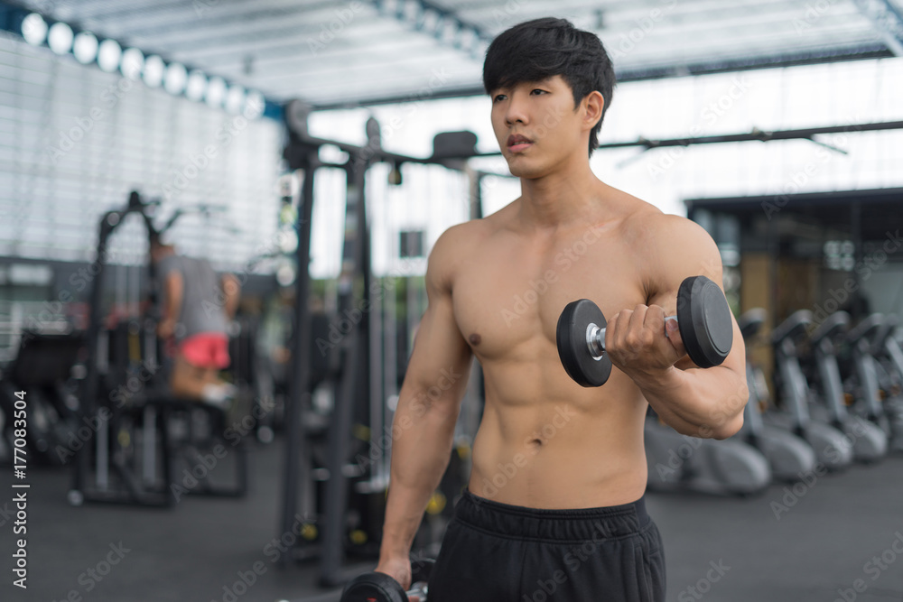 Fitness man in training showing exercises with dumbbells in gym Fitness man in training showing exercises with dumbbells in gym
