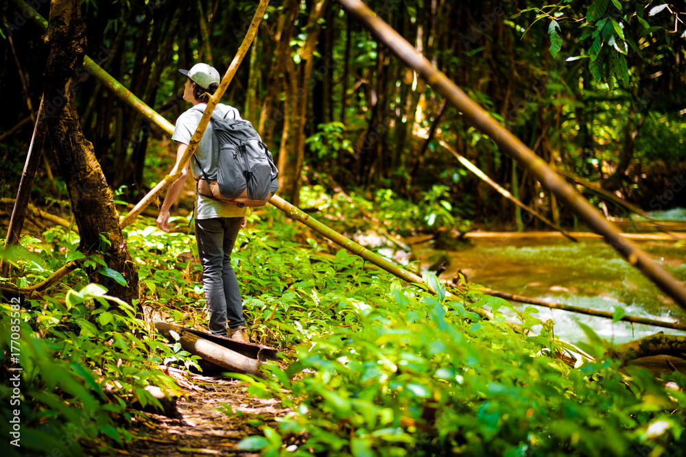 Man traveler traveling walking with backpack at the jungle on holiday at weekend on background nature view Man traveler traveling walking with backpack at the jungle on holiday at weekend on background nature view