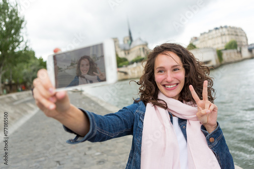 Young woman on holidays in Paris taking selfie in front on Notre Dame - Tourism concept