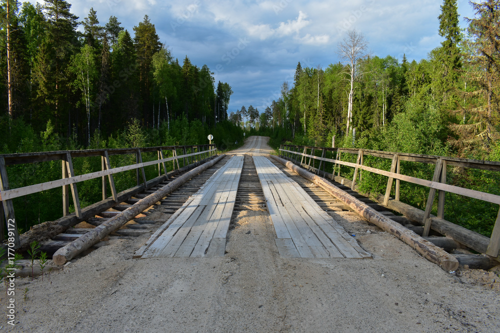 Old wooden bridge in the outback. The old road to the uninhabited village. Old wooden bridge in the outback. The old road to the uninhabited village.