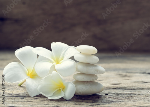 Pile of white zen stones and Frangipani flower  on rustic wood background retro effect