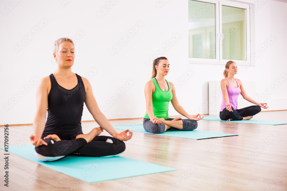 Three girls practicing yoga, Padmasana / Lotus Position Three girls practicing yoga, Padmasana / Lotus Position