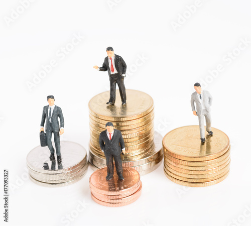 Miniature business people stand on money coins isolated on white,Business success and leadership concept