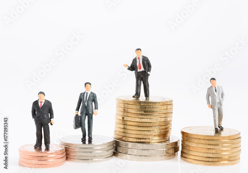 Miniature business people stand on money coins isolated on white,Business leadership concept