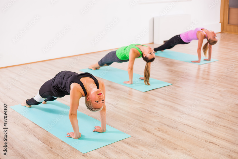 Three girls practicing yoga, Setuasana / Bridge pose Three girls practicing yoga, Setuasana / Bridge pose